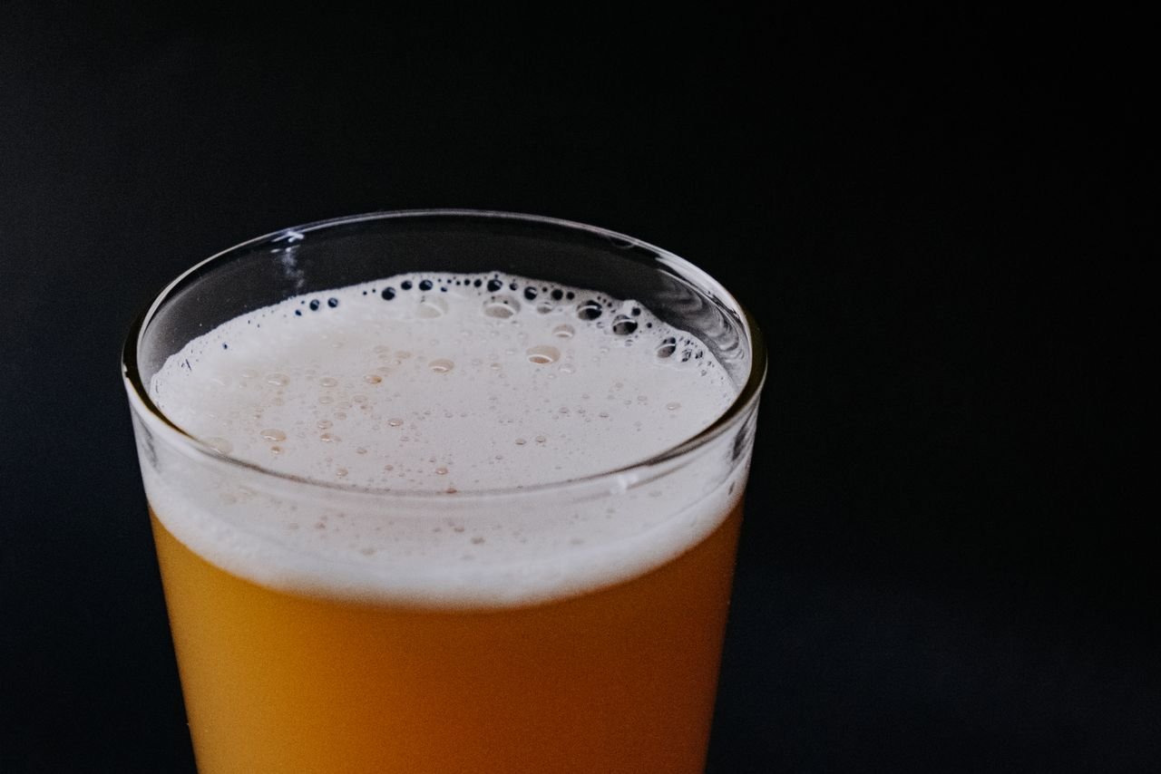 A rich amber-red ale in a pint glass against a dark background, showing the style's deep copper color