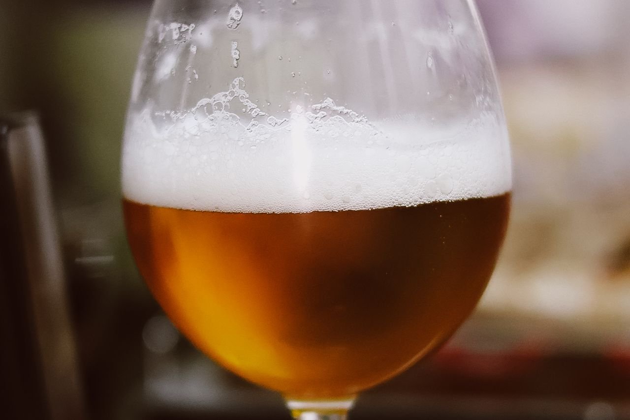 A glass of golden craft beer with a foamy white head viewed from the side