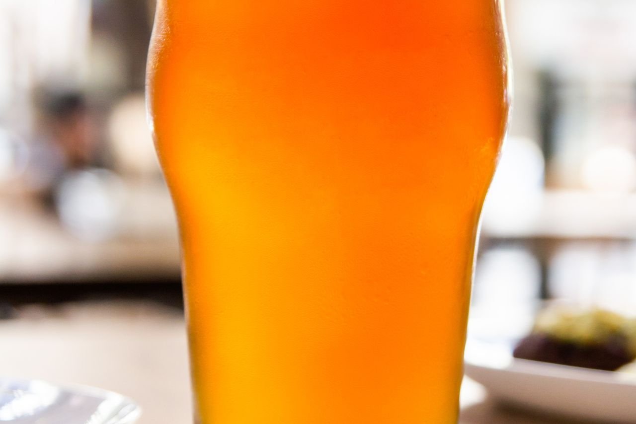 A golden craft beer held up against warm sunlight, showcasing seasonal color