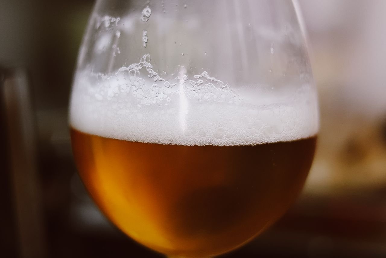 A lager poured into a wine glass showing a golden color and detailed label