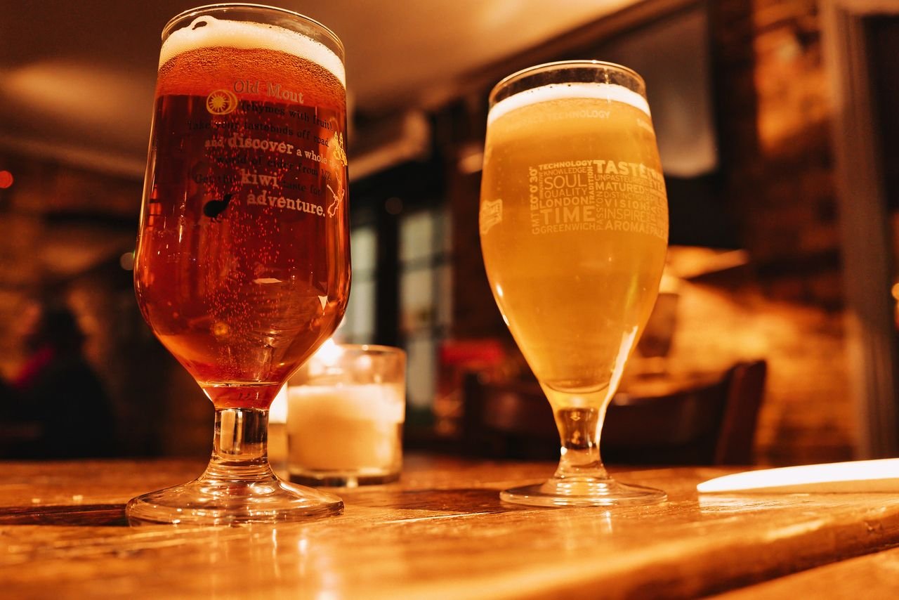 Two wheat beers side by side on a pub table, one hazy and one clear