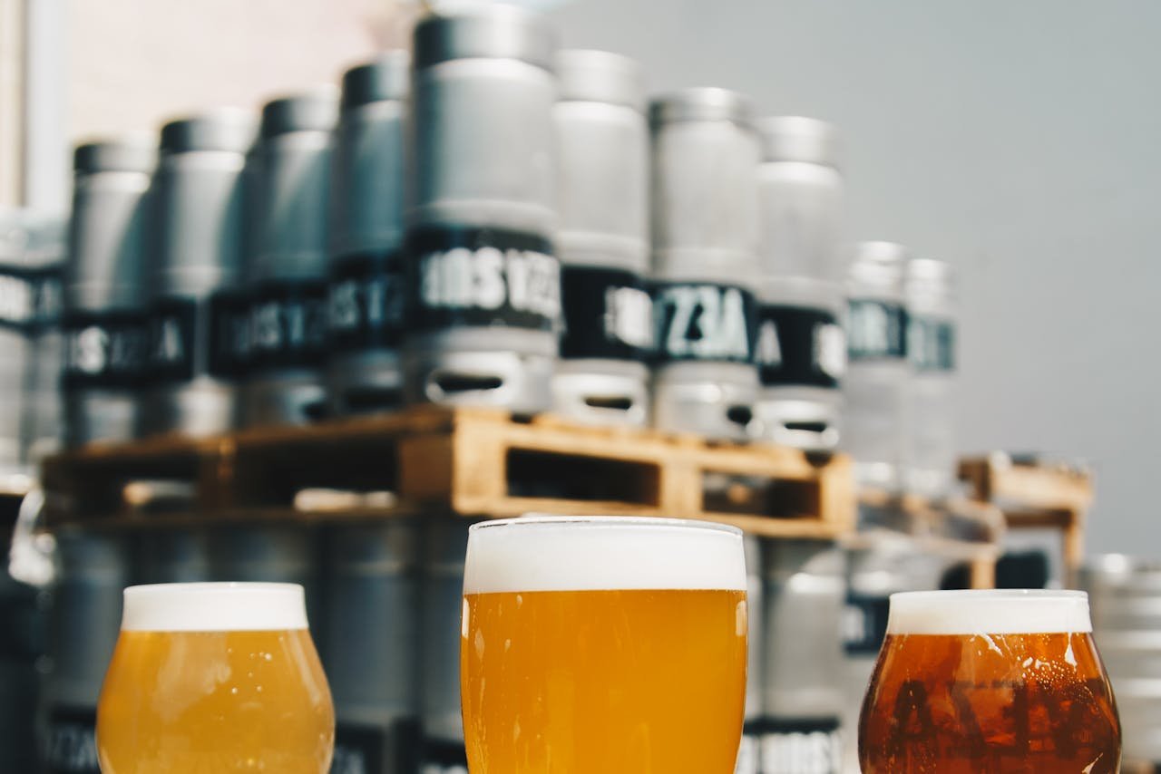 A flight of golden craft beers in front of brewery tanks