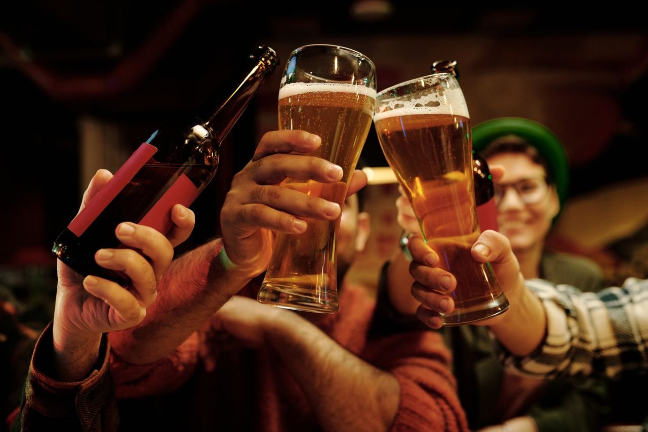 A group of friends raising glasses of different beers in a cheerful pub setting
