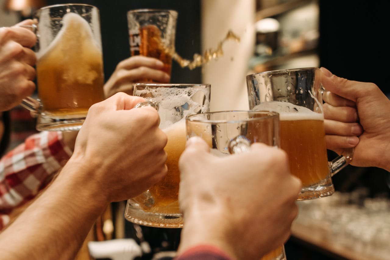 Friends toasting with large mugs of beer, smiling at a brewery table