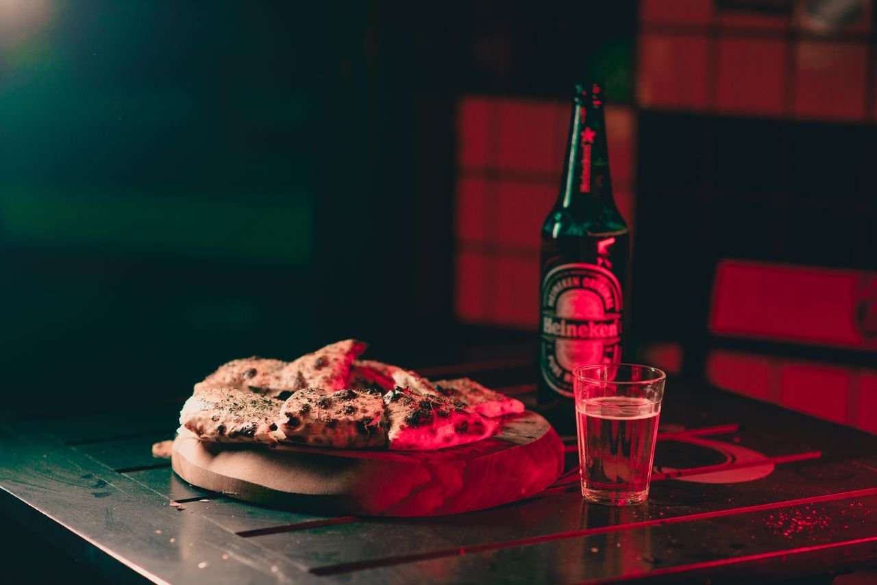 Pizza and a cold pint on a wooden table, a modern enjoyment of an ancient drink